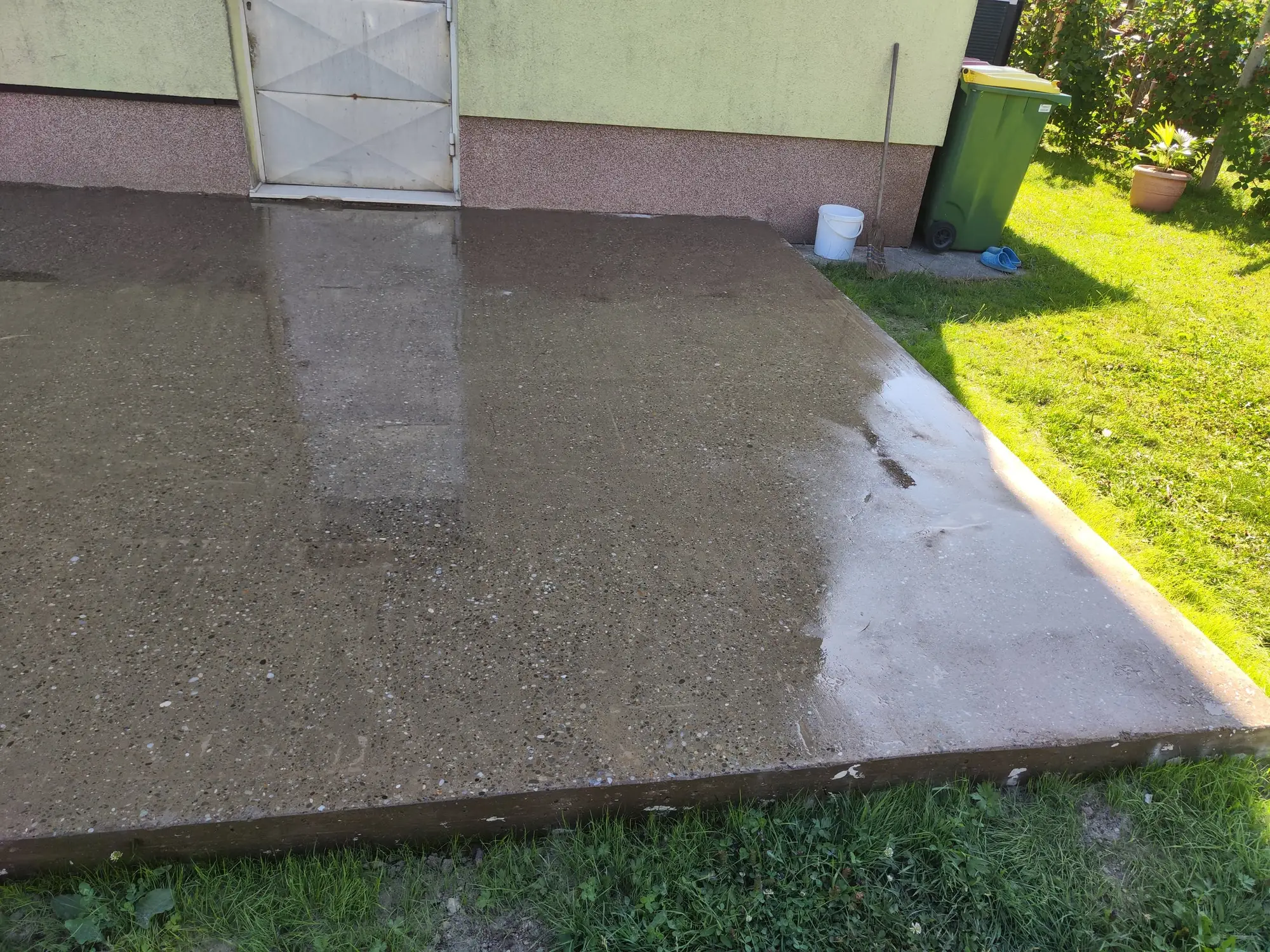 Zbrušena in izravnana betonska terasa ob hiši, mokra površina